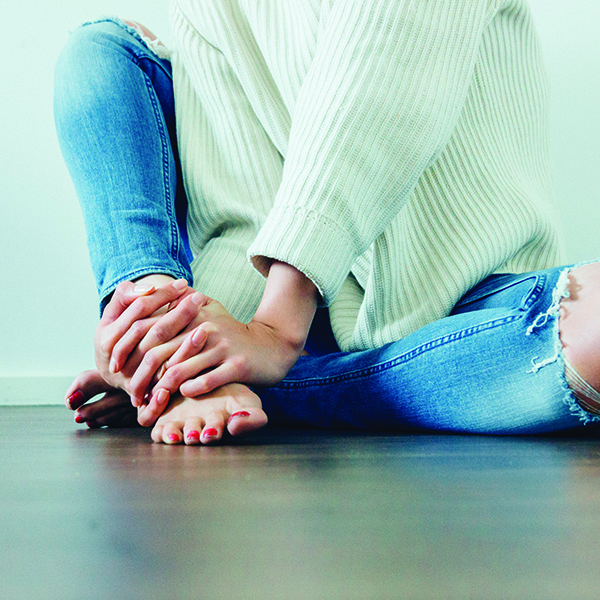 Woman in a depressed pose sitting cross-legged with bare feet